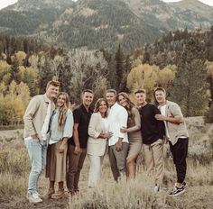 a group of people standing next to each other in a field with mountains in the background