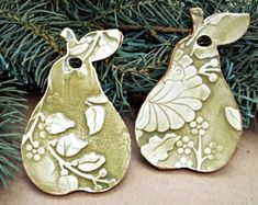 two ceramic ornaments hanging from a christmas tree