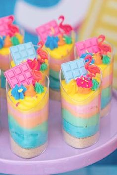 colorful desserts are arranged in small cups on a purple platter at a birthday party