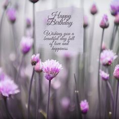 purple flowers with a happy birthday card in the middle, surrounded by white and pink flowers