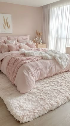 a bedroom with a large bed covered in pink comforters and fluffy rugs on the floor