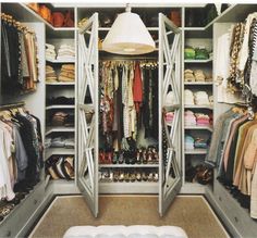 an organized closet with clothes and shoes on the shelves, lights hanging from the ceiling