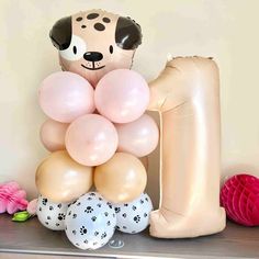 Cute puppy dog latex balloon tower for baby showers and birthday party decorations in rose, sand, coffee and cow print with flower and a coordinating number balloon Puppy Party Centerpieces, 1st Bday Puppy Theme, Puppy Balloon Garland, Pink Puppy Birthday Party, 2nd Birthday Puppy Theme, Kids Puppy Birthday Party, Pink Puppy Party, Puppy Themed Baby Shower Ideas, Lets Pawty Birthday Theme