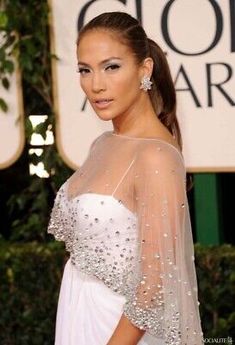 a woman in a white gown and veil on the red carpet at an awards event