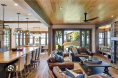 a living room filled with lots of furniture and a fire place next to a kitchen