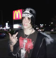 a young man in a black shirt and hat making the peace sign with his hand