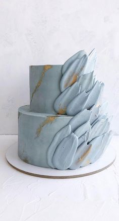 a three tiered cake with blue icing and gold sprinkles on top