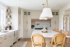 a kitchen with an island and wicker chairs in the center, along with white cabinets