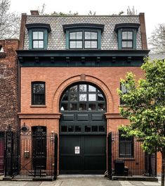 a large brick building with an arched doorway and black iron fence around the front door