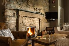 a living room filled with furniture and a fire place in front of a stone wall