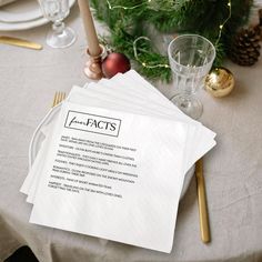 the place setting is set with napkins and gold cutlery, along with pine cones