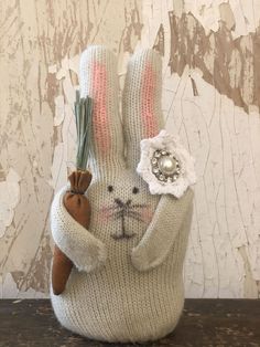 a knitted bunny holding a flower in it's hand on top of a wooden table