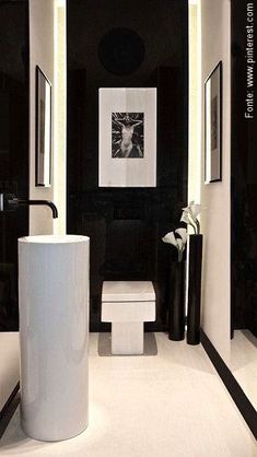 a white toilet sitting next to a sink in a bathroom under two framed pictures on the wall