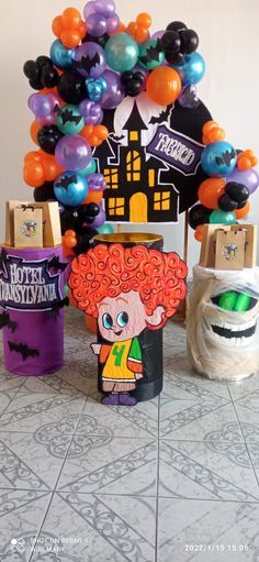 there are balloons and decorations on the floor in front of a halloween tree with an orange wig