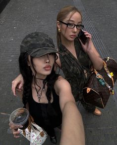 two women sitting on the ground talking on their cell phones