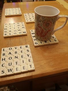 a coffee cup sitting on top of a wooden table next to scrabble tiles