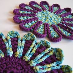 two crocheted flower coasters sitting next to each other