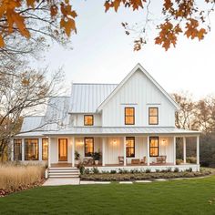 a white house with lots of windows on the front and side of it, surrounded by grass