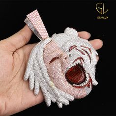 a hand holding a white and red beaded purse with an angry clown face on it