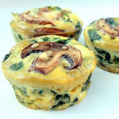 three muffins with spinach and bacon on top sitting on a white plate