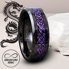 a black and purple dragon ring with an intricate design on the inside is next to a rock