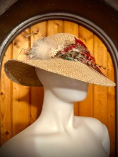 Designed by couture milliner Diane Feathersmith, this hat is a rare gem with an assortment of feathers in fantastic condition and a spiral shell embellishment. It's flamboyant and provides stylish sun protection with its 3 inch wide dramatically sloping brim.  Details: size: M, 22 5/8 inches  Assorted natural feathers: Red Rooster, Rooster pluma, and Grouse feathers Condition: Excellent, without any damage, stains or wear. Vintage Handmade Costume Hats And Headpieces, Vintage Handmade Brimmed Costume Hat, Handmade Vintage Brimmed Costume Hats, Vintage Festival Hat With Feathers, Handmade Vintage Costume Hats For Kentucky Derby, Vintage Flat Brim Straw Hat For Festival, Handmade Vintage Hat-style Fascinator, Vintage Festival Straw Hat With Flat Brim, Handmade Vintage Hat Fascinator