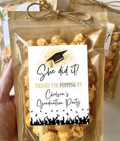 someone holding up a bag of popcorn with graduation party tags on it's side