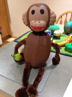 a stuffed monkey sitting on top of a table next to a green ball and some toys