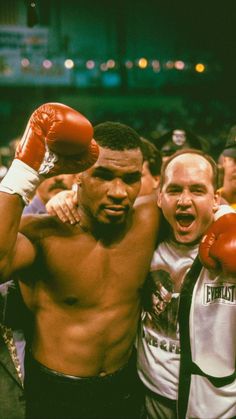 two men standing next to each other with boxing gloves on their shoulders and fists raised