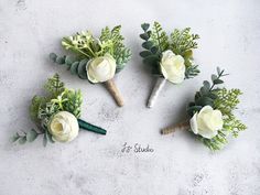 six boutonnieres with white flowers and greenery