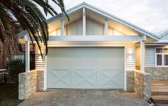 a house with a palm tree in front of it and two garage doors on each side