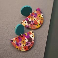 two pairs of colorful earrings sitting on top of a table