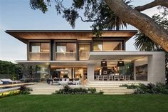 a modern house with large trees in the front yard