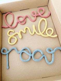 the word smile spelled out in crocheted letters are sitting inside a box with string