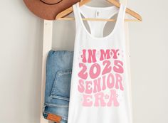 In My 2025 Senior Era Tank Top, Senior 2025 Shirt, Senior Class of 2025, Pink Senior Shirt, Cute Pink Senior Shirt For Girls, Grad Shirt 2025 Pink, Senior Era, High School Things, Grad Shirts, Senior Shirts, Class Of 2025, School Things, Scooped Neckline, Workout Tank Tops