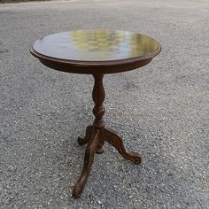 a small wooden table sitting on top of a gravel road next to a parking lot