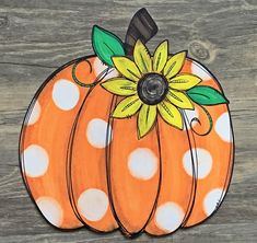 an orange and white polka dot pumpkin painted on wood