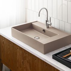 a bathroom sink sitting on top of a counter next to a brush and soap dispenser