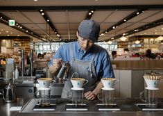 a man in an apron pours coffee into cups