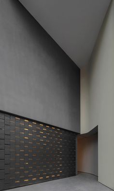 an empty room with black and gold tiles on the wall, next to a bench