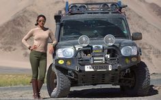 a woman standing next to a vehicle in the desert