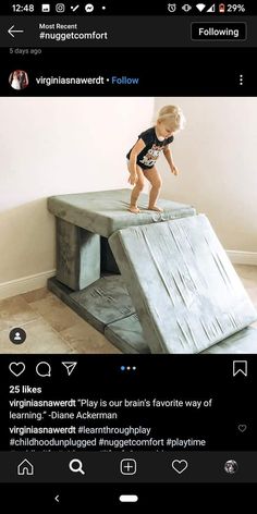 a toddler standing on top of a wooden ramp in the middle of a room