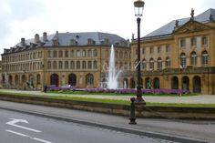 a large building with a fountain in front of it on the side of a road