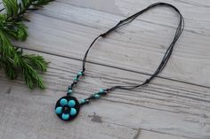 a black and blue necklace with flowers hanging from it's side on a wooden surface