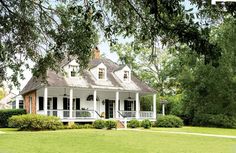 a large white house sitting in the middle of a lush green field with lots of trees