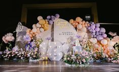 an image of a birthday party with balloons and flowers on the stage at night time