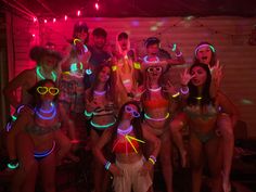 a group of people standing around each other with neon lights on their heads and arms