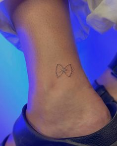 a woman's foot with a small bow tattoo on the side of her ankle