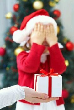 a person holding a present in front of a christmas tree