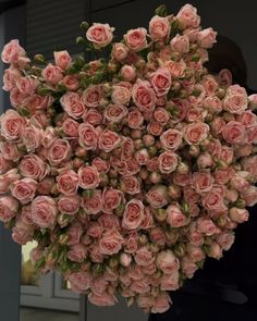 a large bouquet of pink roses hanging from the ceiling in front of a building door